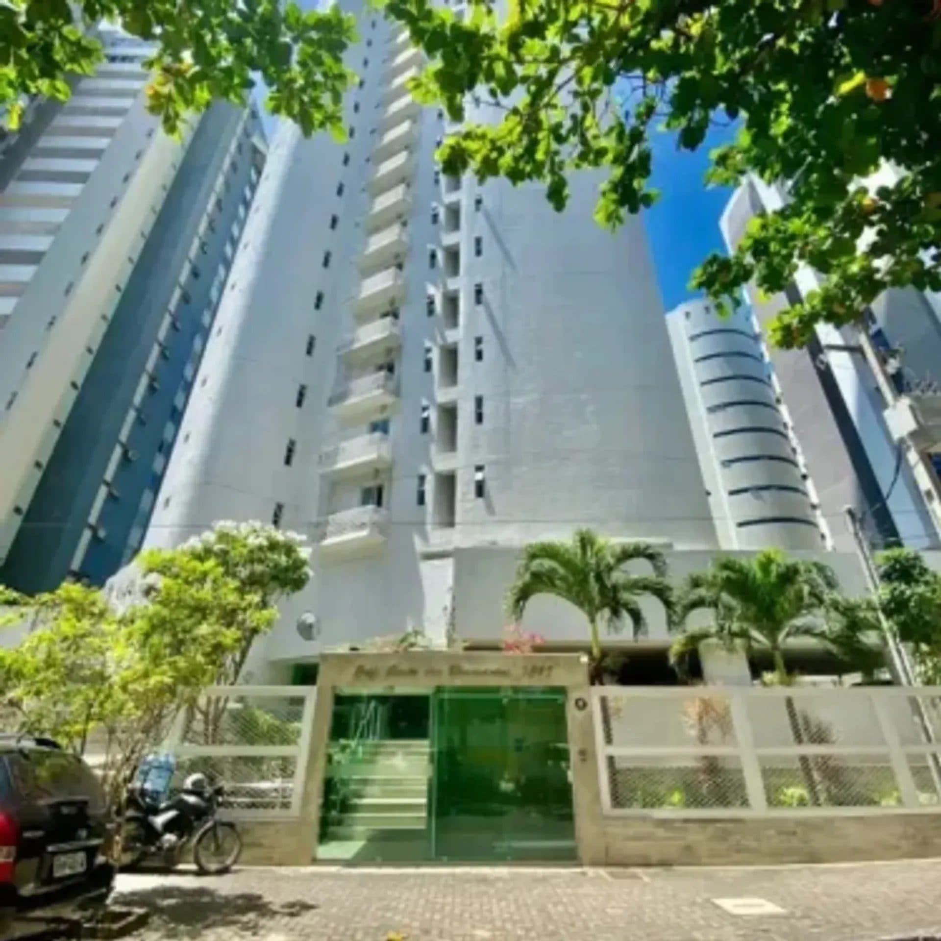 Fachada externa e portaria de edifício com árvores na calçada